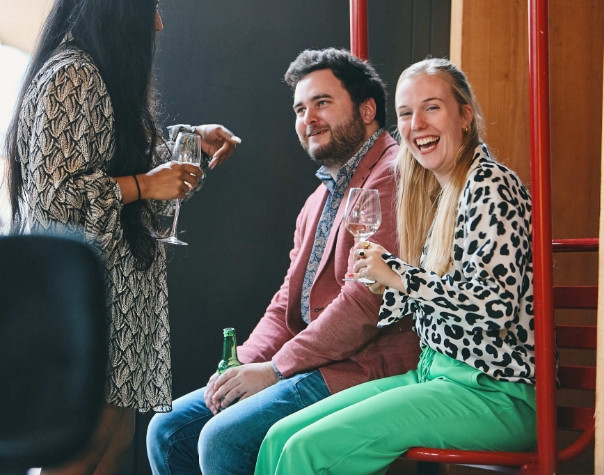 a man and a woman sitting on a chair drinking wine.