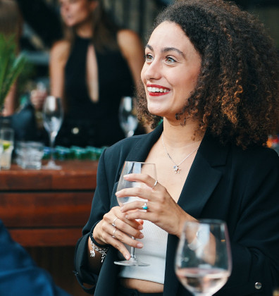 eine Frau, die mit einem Glas Wein an einem Tisch sitzt.